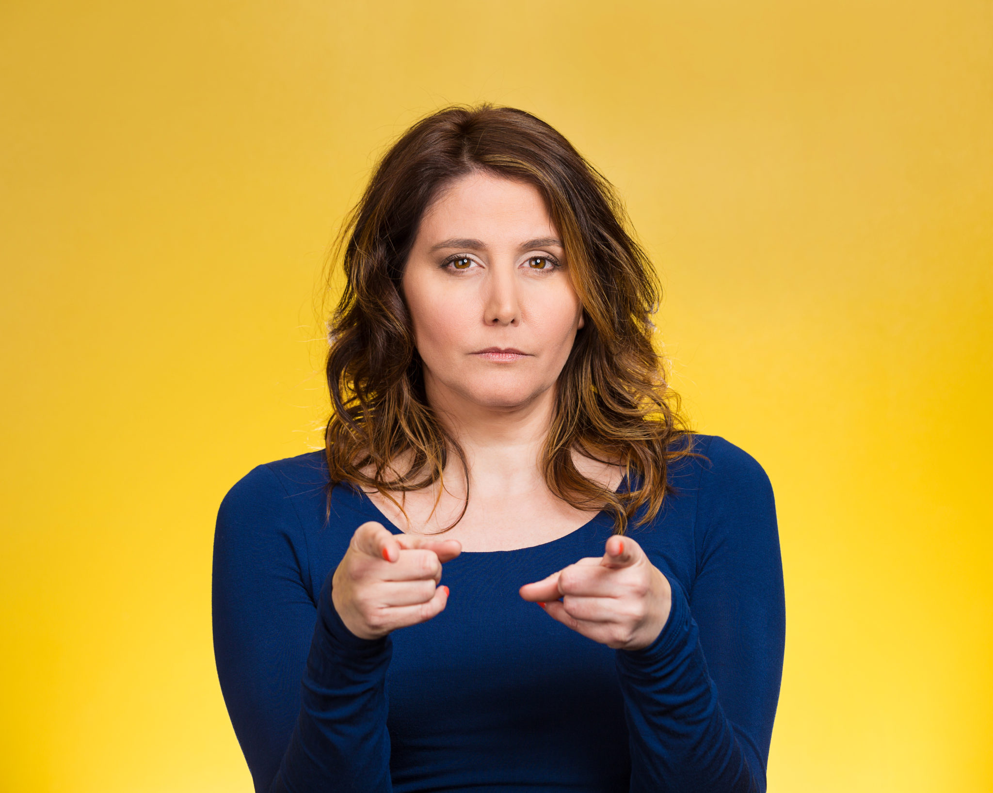 Portrait young, unhappy, serious woman pointing finger at someone, blaming for something wrong, mistake, isolated yellow background. Negative human emotions, facial expressions, feelings, reaction